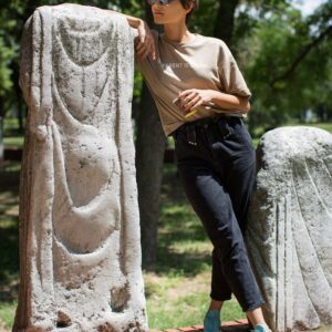 Young woman in a park set against the historical monument posing with espresso take away drink
