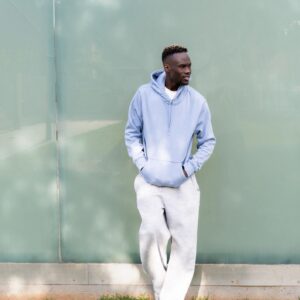 Young man wearing casual clothes is looking away while leaning against a wall