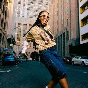 Side view of a confident and joyful young woman dancing playfully in the middle of a city street