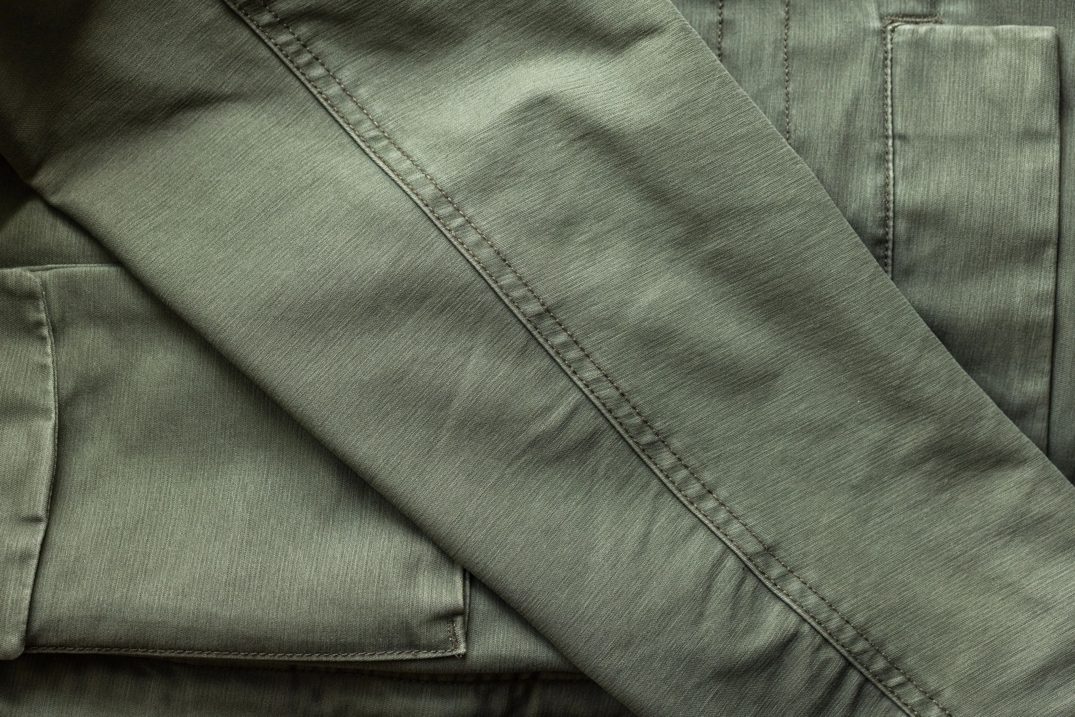Close-up detail of olive green jacket fabric and pocket